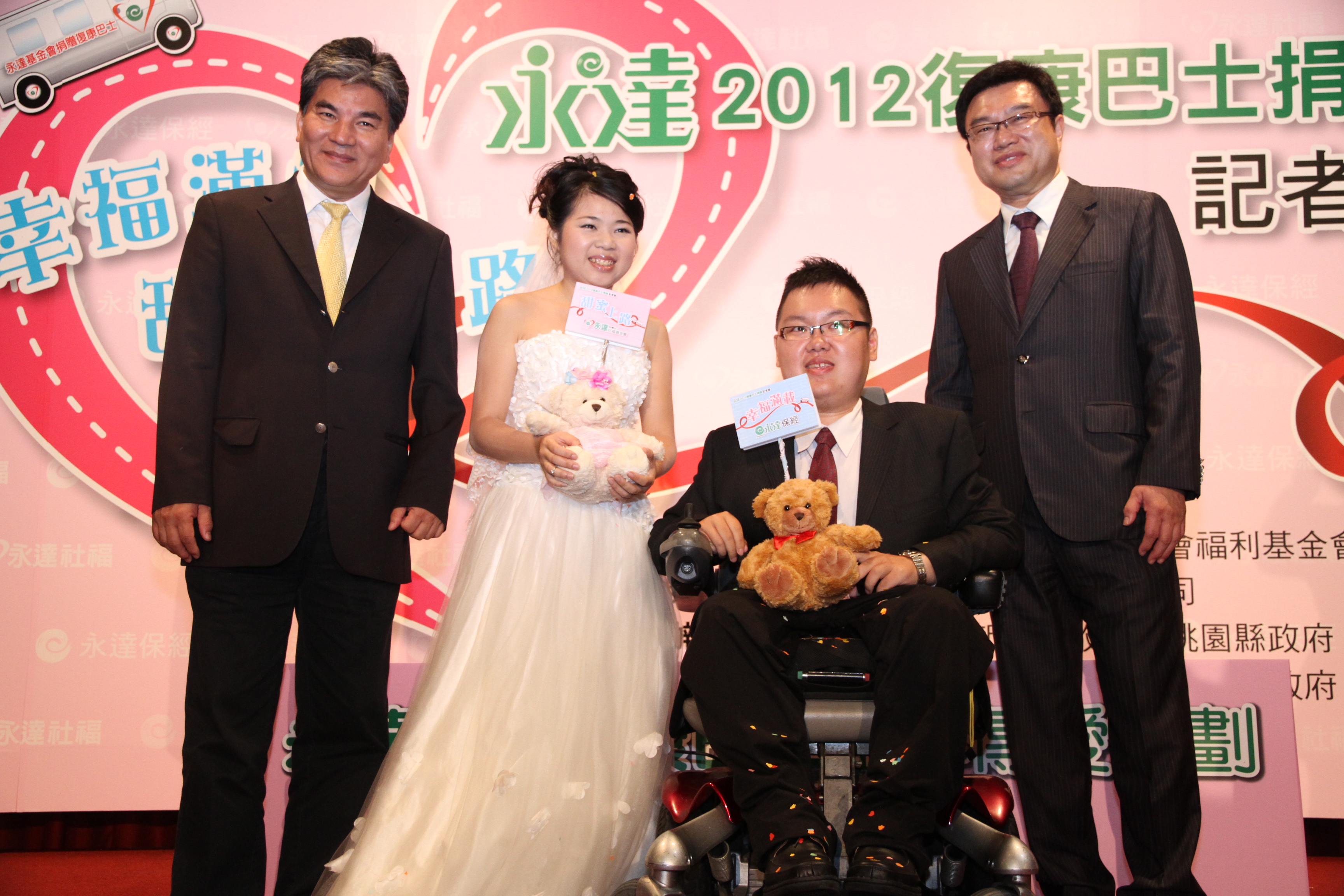 內政部部長李鴻源(左一)與永達吳文永董事長(右一)獻上幸福甜蜜小熊為身障新人小齊(右二)與誼芳(左二)見証求婚儀式。