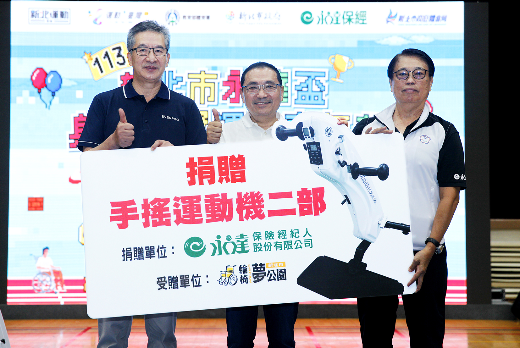 左起永達保經捐贈兩台手搖運動機，由陳慶鴻總經理代表捐贈、新北市政府侯友宜市長見證、中華民國身心障礙者休閒運動推廣協會林永華理事長代表受贈。