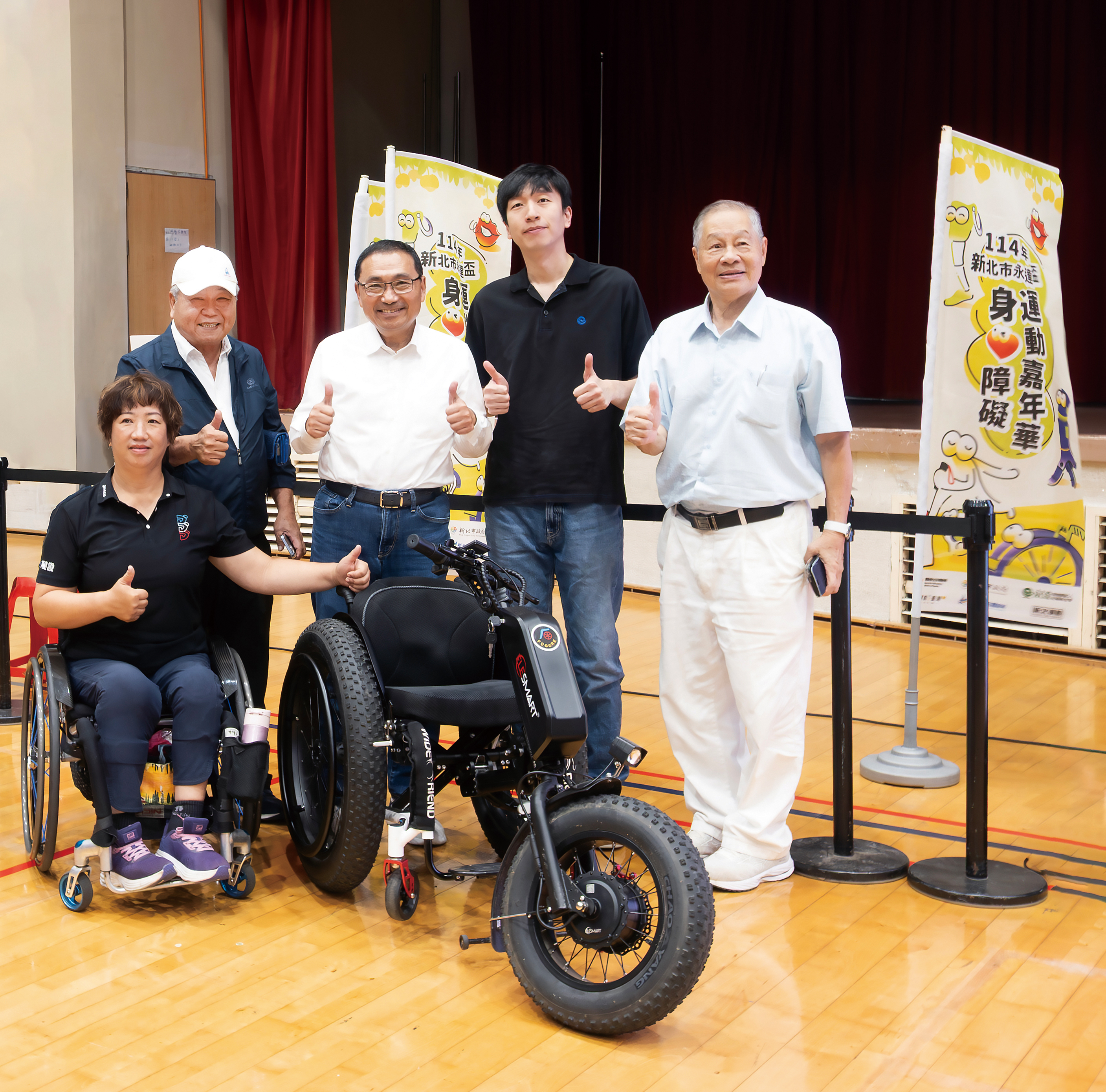 侯友宜市長(中)、吳柏瑨總經理特助(右2)、呂嘉儀營運長(左1)、中華民國身心障礙者休閒運動推廣協會劉耀台副理事長(左2)、張思敏名譽理事長(右1)與本次捐贈的沙灘輪椅合影留念。